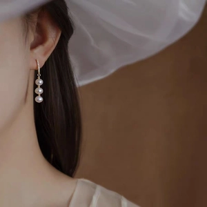 Elegant gold drop earrings with three round white pearls and sparkling cubic zirconia stones