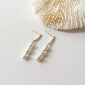 Macro shot of 925 silver gold-plated earrings with zircon and triple freshwater pearls