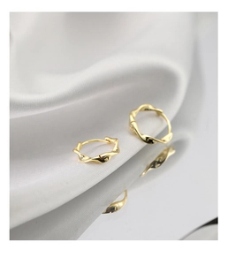 Macro view of gold Mobius hoop earrings with twisted design and polished mirror finish