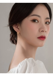 Close-up of golden twist hoop earrings with textured Mobius design on a model