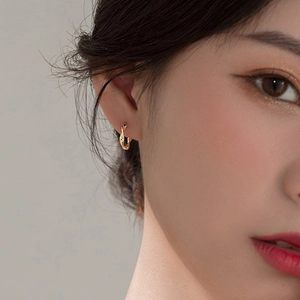 Minimalist twisted gold hoop earrings with Moebius design worn on a model's ear