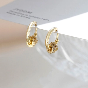 Macro view of gold hoop earrings with sparkling micro-paved cubic zirconia charms