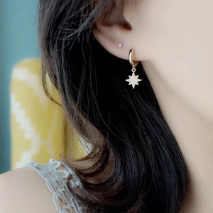 Detail of gold star pendant earrings with pavé crystals worn on model's ear