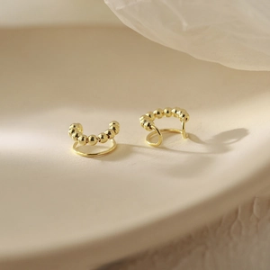 Macro di un ear cuff dorato a doppio strato con piccole perle in metallo per orecchie non forate