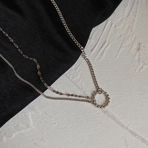 Detail of double-layer S925 silver necklace with beaded circle pendant on chic background