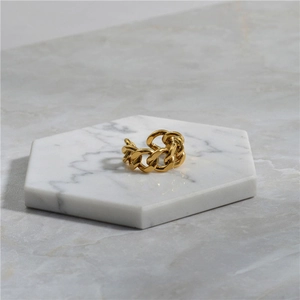 Close-up of golden Cuban link chain ring with a polished finish on marble tray