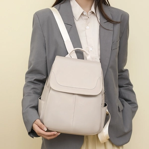 Detail view of beige Oxford fabric backpack with wide shoulder strap and flap design