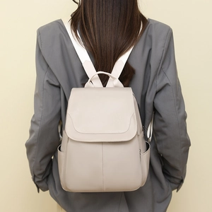 Detail of beige Oxford cloth backpack with leather texture and flap closure