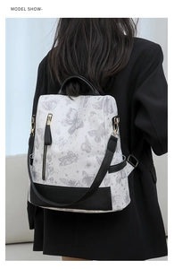 Rear view of model wearing white nylon backpack with butterfly print and black trim