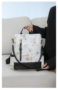 Detail of white nylon backpack with butterfly print and black leather accents