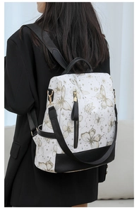 Detailed back view of a white nylon backpack with elegant golden butterfly and star patterns