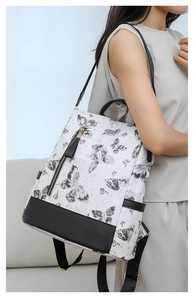 Side view of white nylon backpack with black floral embroidery and leather trim