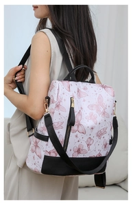 Fashionable floral backpack with purple butterfly print and black contrast straps shown on model