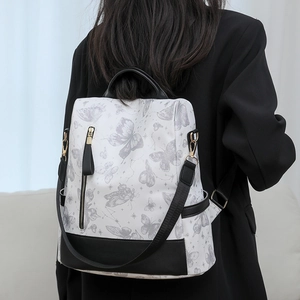 Modern white backpack with gray butterfly print worn over a classic black blazer