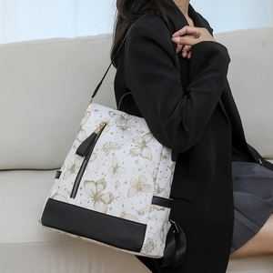 Detail of white nylon backpack with gold butterfly patterns and black leather bottom
