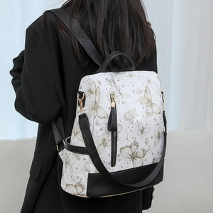 Detail of embroidered butterfly pattern on white nylon backpack with gold hardware