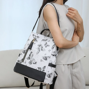 Detail of a nylon backpack with butterfly embroidery and black leather base on a model