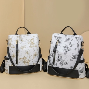 Detail view of two nylon backpacks featuring gold and black butterfly embroidery patterns