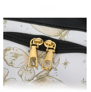Detailed macro shot of durable black dual zippers and gold-tone pullers on a white nylon bag