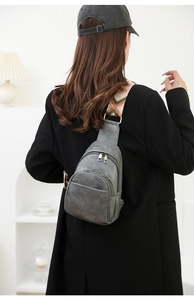 Detalle de bandolera vintage gris oscuro en cuero sintético con correa tejida en modelo