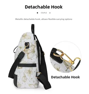 Detail of detachable gold-tone metal hooks on a white nylon backpack with butterfly print