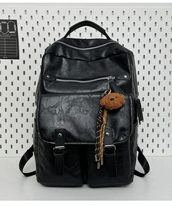 Detail of black pebbled PU leather backpack with multiple metal zippers and plush bear charm