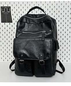 Detail of black faux leather backpack featuring dual magnetic buckles and zipper compartments