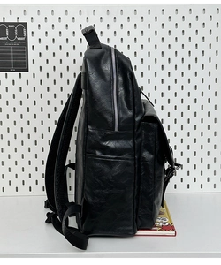Side view of black pebble leather backpack featuring silver metal zippers and side pocket