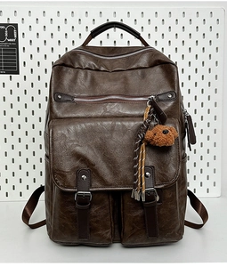 Detail view of dark brown PU leather backpack with vintage texture and plush bear charm