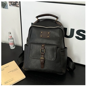Detail of vintage black leather backpack with brown straps and aged bronze hardware
