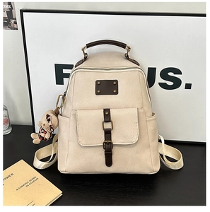 Detail view of cream white PU leather backpack with vintage brown straps and bear charm