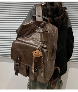 Detailed back view of a dark brown PU leather laptop backpack with a cute bear charm