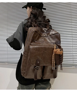 Detail of dark brown retro laptop backpack with leather texture and bear charm
