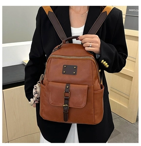 Detail of vintage brown leather backpack with leopard bear charm and metal buckle straps