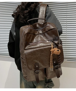 Close-up of retro brown PU leather backpack with vintage textures and plush bear charm