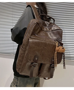 Detail of dark brown vintage leather backpack with texture and bear charm