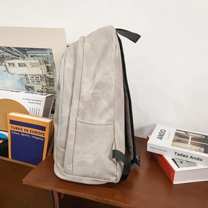 Side view of light gray minimalist backpack with smooth matte texture and adjustable straps