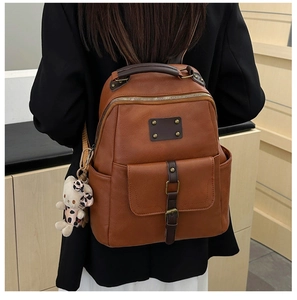 Close-up of vintage brown PU leather backpack featuring bronze rivets and cat charm detail