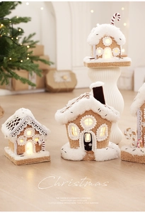 Close-up of glowing gingerbread house with warm LED lights and snowy roof detail
