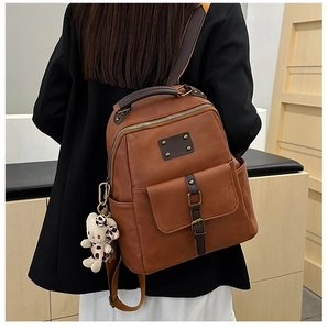 Detail of vintage brown faux leather backpack with plush kitty charm and bronze hardware