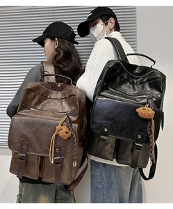 Close-up of retro leather backpacks in black and brown with cute bear keychain pendant