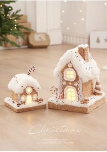 Close-up of glowing gingerbread house decorations with faux snow and candy details