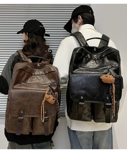Rear view of large vintage textured leather backpacks in black and brown with bear charms