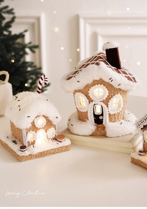 Macro detail of gingerbread house decor with faux snow roof and warm LED windows