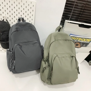 Detail of waterproof nylon backpack showing large front zipper pocket and side storage
