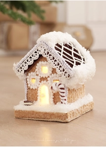 Close-up of lighted gingerbread house with snow roof and red candy cane detail