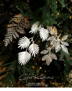 Détail de feuilles de fougère de Noël dorées scintillantes sur sapin illuminé chaud