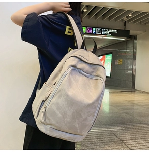 Detailed back view of a large light grey travel backpack with multi-pocket design on subway