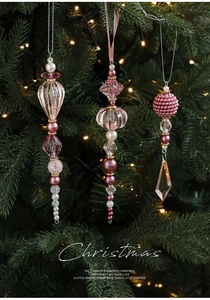 Gros plan d'ornements en perles de cristal acrylique rose sur un sapin de Noël illuminé