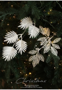 Gros plan de feuilles de fougère blanches pailletées et chaîne de perles sur sapin